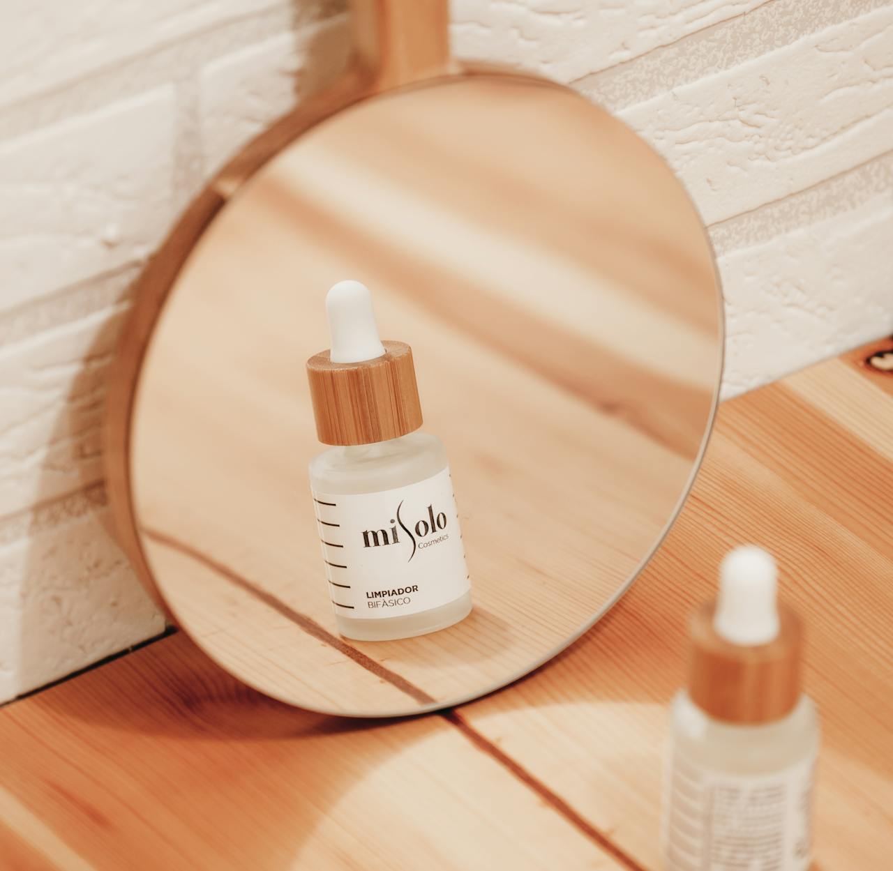 Close-up of a skincare product reflected in a mirror on a warm wooden surface.