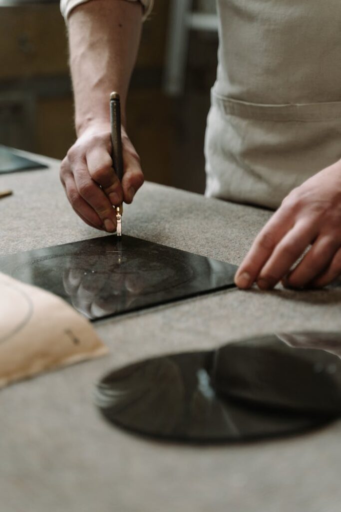 Skillful artisan cutting glass sheet by hand, showcasing craftsmanship in a workshop setting.
